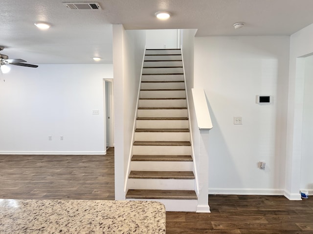 staircase featuring hardwood / wood-style flooring, ceiling fan, and a textured ceiling