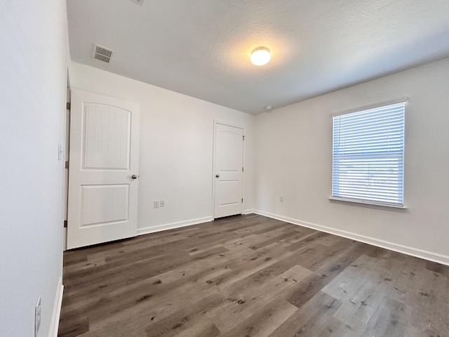 unfurnished room with dark hardwood / wood-style flooring and a textured ceiling