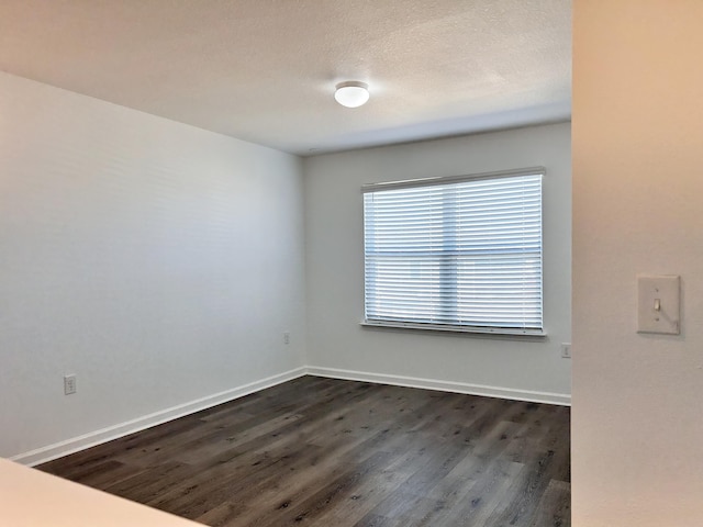 empty room featuring dark wood-type flooring and a textured ceiling