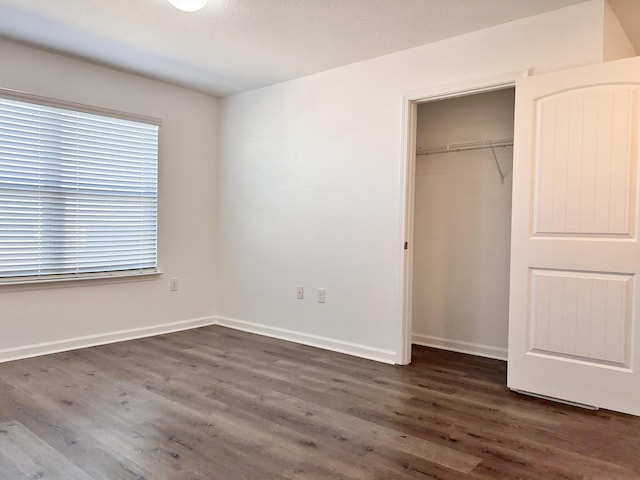 unfurnished bedroom featuring dark wood-type flooring and a closet