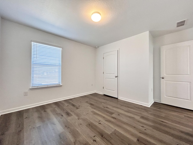 spare room featuring dark hardwood / wood-style floors and a textured ceiling