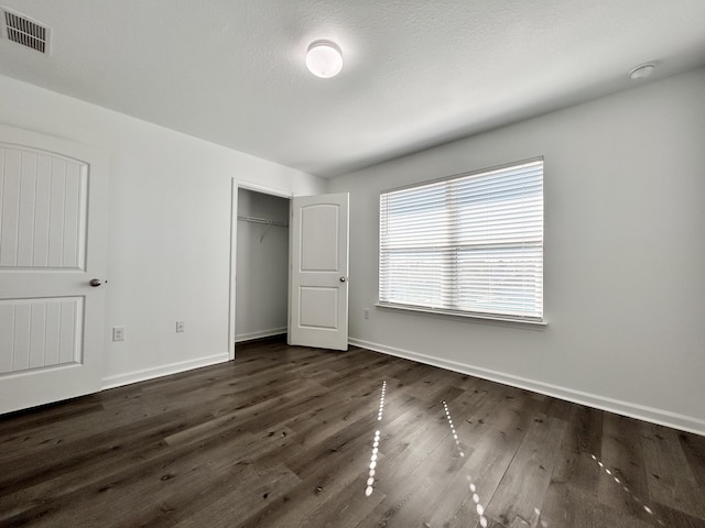 unfurnished bedroom featuring dark wood-type flooring and a closet