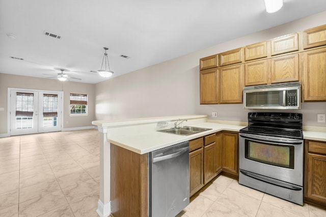 kitchen with stainless steel appliances, sink, french doors, kitchen peninsula, and hanging light fixtures