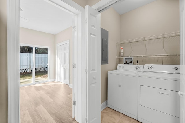 clothes washing area featuring washing machine and dryer, electric panel, and light hardwood / wood-style floors