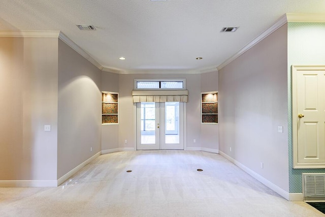 empty room with light carpet, a textured ceiling, crown molding, and french doors