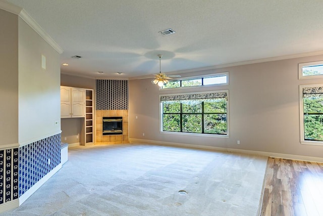 unfurnished living room featuring ceiling fan, a tile fireplace, and crown molding