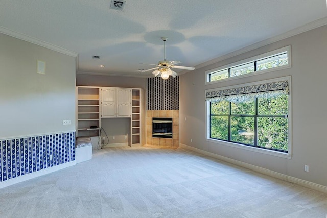 unfurnished living room with ceiling fan, light colored carpet, a fireplace, and crown molding