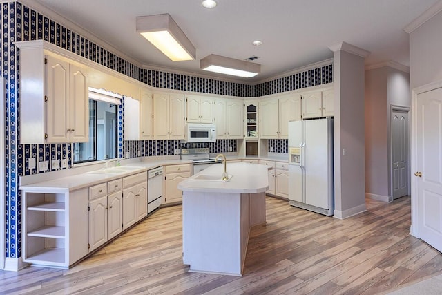 kitchen featuring light hardwood / wood-style floors, an island with sink, white appliances, ornamental molding, and sink