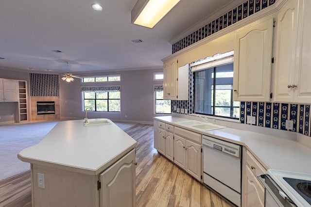 kitchen featuring a fireplace, dishwasher, sink, and a kitchen island