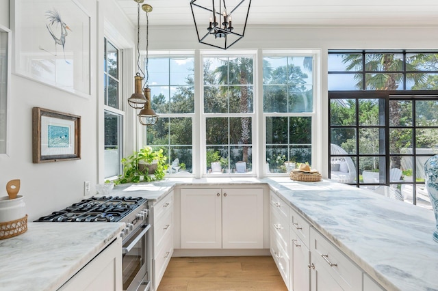 kitchen featuring light stone countertops, stainless steel range with gas cooktop, pendant lighting, and white cabinets