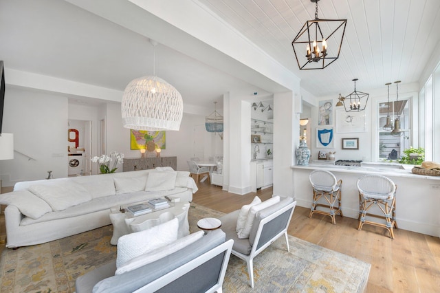 living room with independent washer and dryer, light hardwood / wood-style floors, wood ceiling, an inviting chandelier, and sink