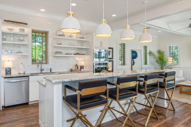 kitchen featuring appliances with stainless steel finishes, pendant lighting, a breakfast bar, sink, and white cabinetry