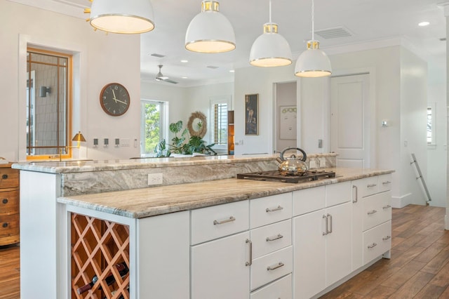 kitchen featuring hanging light fixtures, crown molding, ceiling fan, stainless steel gas stovetop, and white cabinets