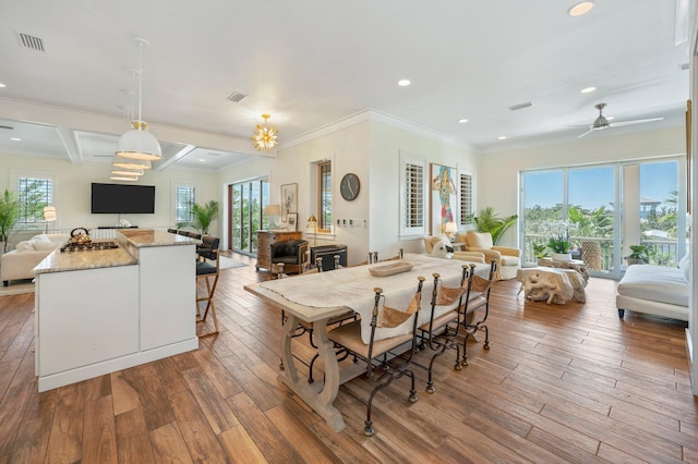 dining area featuring ceiling fan with notable chandelier, hardwood / wood-style flooring, and ornamental molding