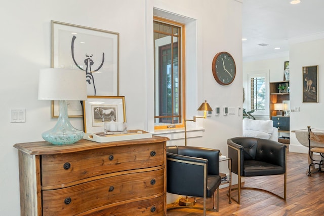 living area with ornamental molding and hardwood / wood-style flooring