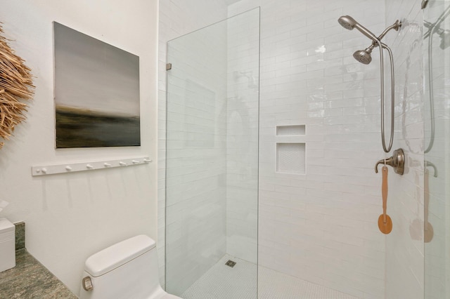 bathroom with a tile shower and toilet