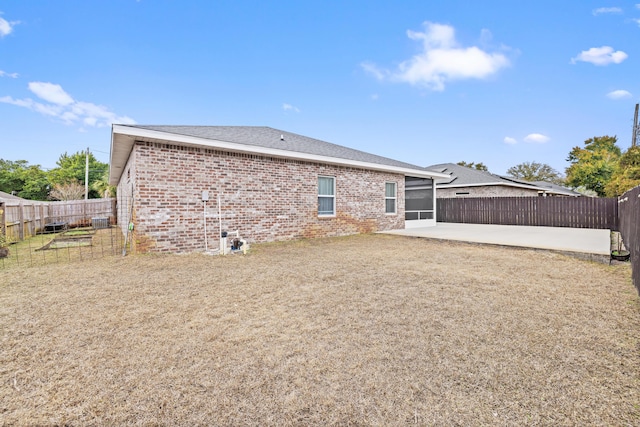 rear view of house featuring a lawn, a sunroom, and a patio