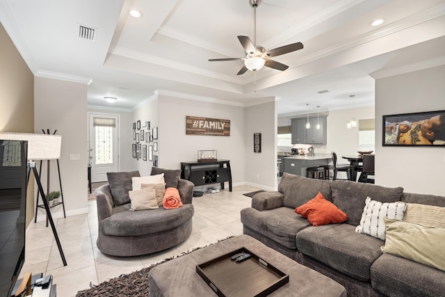 living room featuring crown molding, light tile patterned floors, a tray ceiling, and ceiling fan