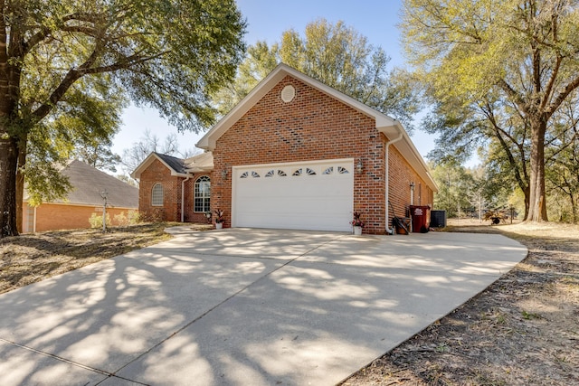 view of front of house with brick siding, central AC, concrete driveway, and an attached garage