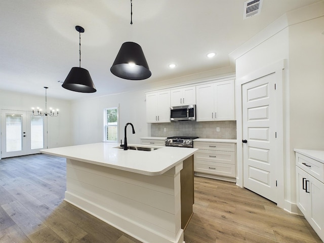 kitchen with light wood finished floors, tasteful backsplash, visible vents, appliances with stainless steel finishes, and a sink