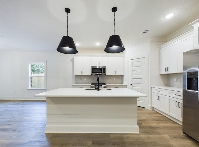 kitchen with appliances with stainless steel finishes, light countertops, visible vents, and wood finished floors