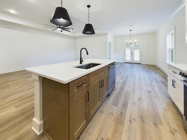 kitchen with light wood-style flooring, open floor plan, a sink, light countertops, and stainless steel dishwasher