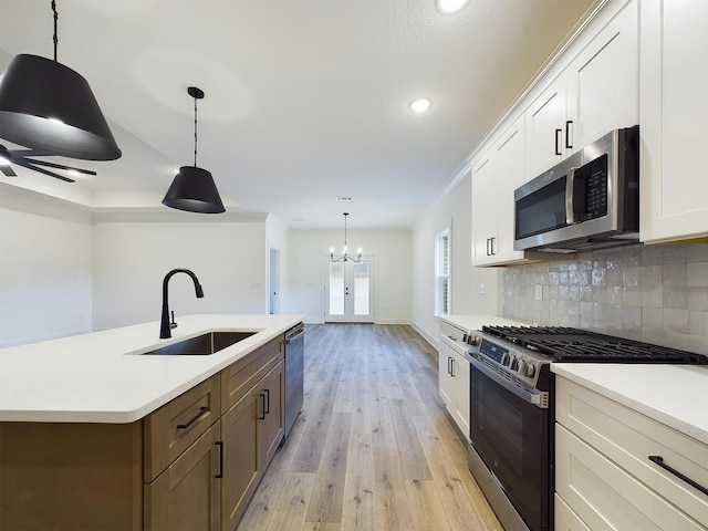 kitchen featuring light wood-style flooring, a sink, light countertops, appliances with stainless steel finishes, and tasteful backsplash