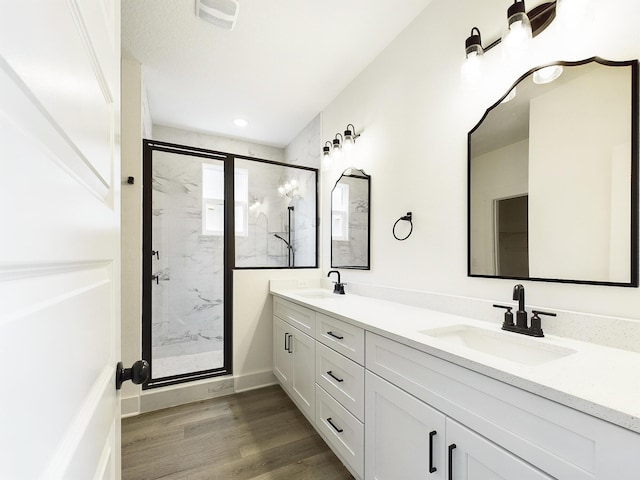 bathroom with a marble finish shower, visible vents, a sink, and wood finished floors