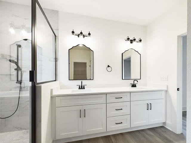 full bathroom featuring wood finished floors, a sink, a shower stall, and double vanity