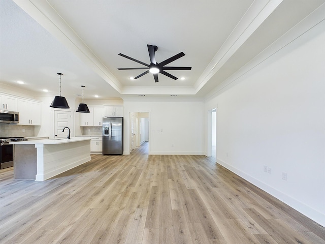 kitchen with appliances with stainless steel finishes, a tray ceiling, a sink, and backsplash