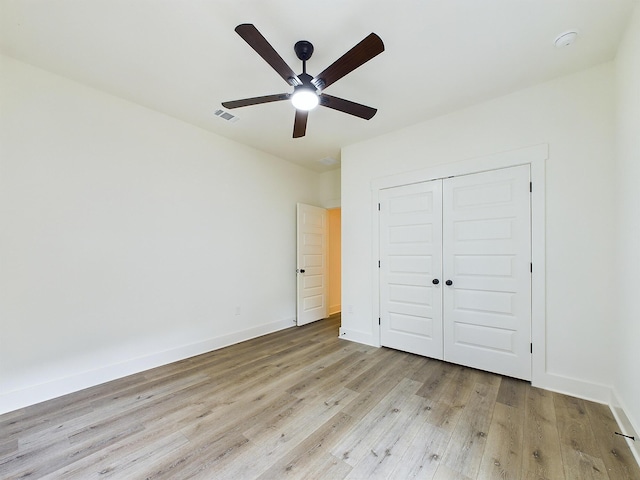 unfurnished bedroom with light wood finished floors, baseboards, visible vents, ceiling fan, and a closet