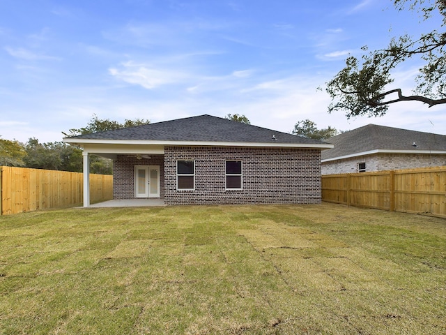 rear view of property with brick siding, a yard, a patio, a shingled roof, and a fenced backyard