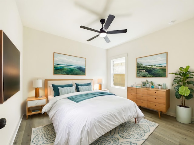 bedroom with light wood-style floors, baseboards, and a ceiling fan