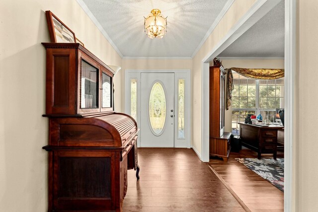 foyer entrance featuring a notable chandelier, ornamental molding, dark wood-type flooring, and a textured ceiling