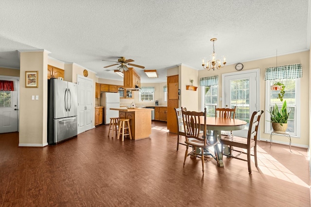 dining space with ceiling fan with notable chandelier, crown molding, dark hardwood / wood-style flooring, and a textured ceiling