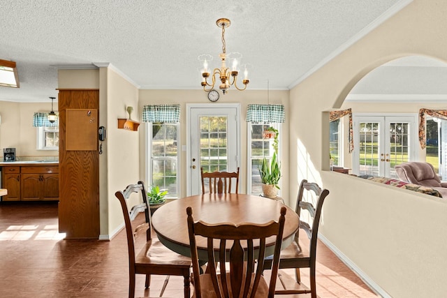 dining room with crown molding, french doors, hardwood / wood-style floors, a textured ceiling, and a notable chandelier