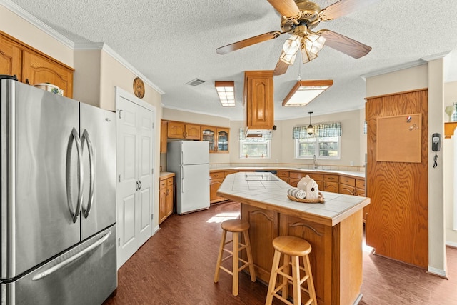 kitchen with a center island, tile counters, white fridge, stainless steel fridge, and crown molding