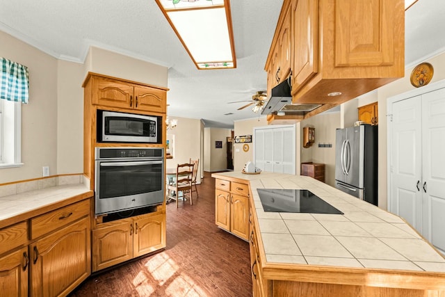 kitchen featuring appliances with stainless steel finishes, tile counters, dark hardwood / wood-style floors, ceiling fan, and crown molding