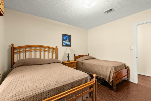 bedroom featuring a textured ceiling and dark hardwood / wood-style flooring