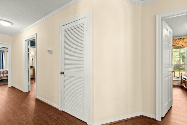 corridor featuring a textured ceiling, ornamental molding, and hardwood / wood-style floors