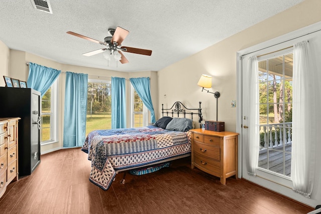 bedroom featuring a textured ceiling, dark hardwood / wood-style floors, access to outside, stainless steel refrigerator, and ceiling fan