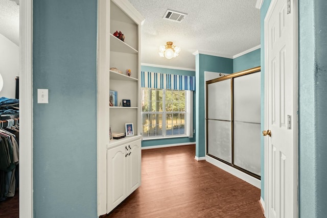 bathroom with crown molding, wood-type flooring, a textured ceiling, and a shower with shower door