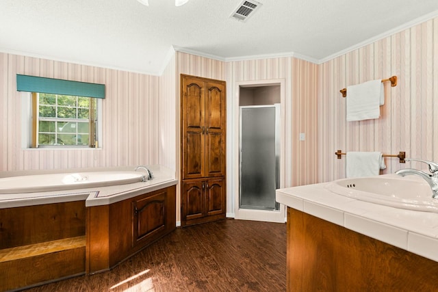 bathroom featuring hardwood / wood-style flooring, ornamental molding, a textured ceiling, shower with separate bathtub, and vanity