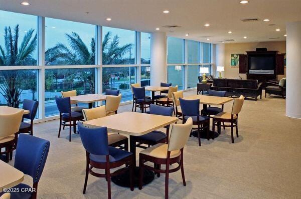 dining space with a wall of windows and light colored carpet