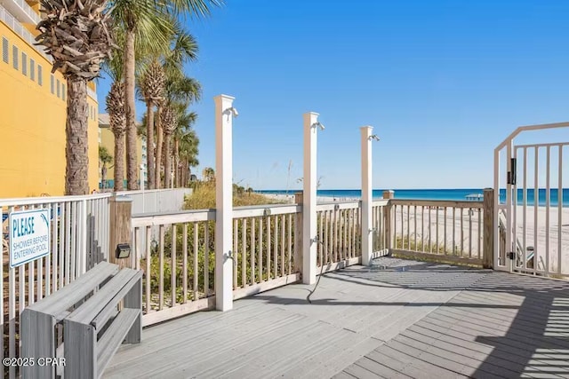 wooden terrace featuring a beach view and a water view