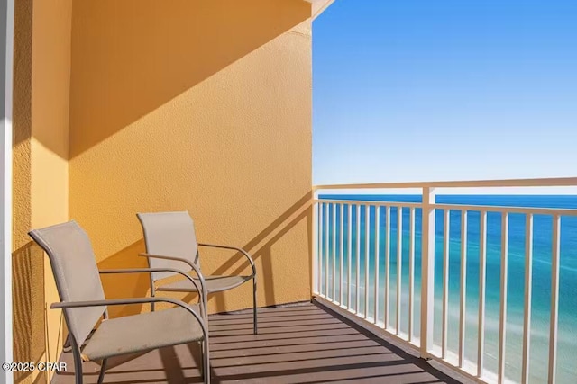 balcony featuring a view of the beach and a water view