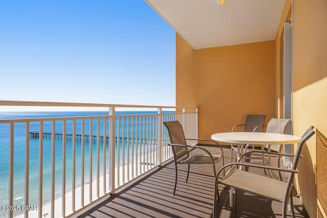 balcony featuring a view of the beach and a water view