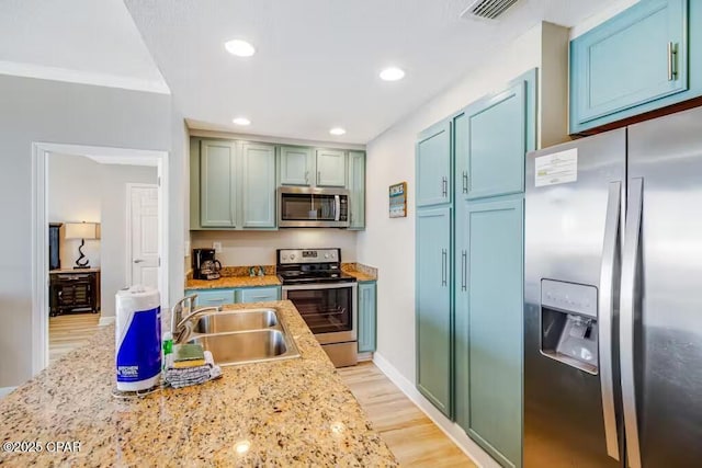 kitchen with appliances with stainless steel finishes, light wood-type flooring, crown molding, light stone countertops, and sink