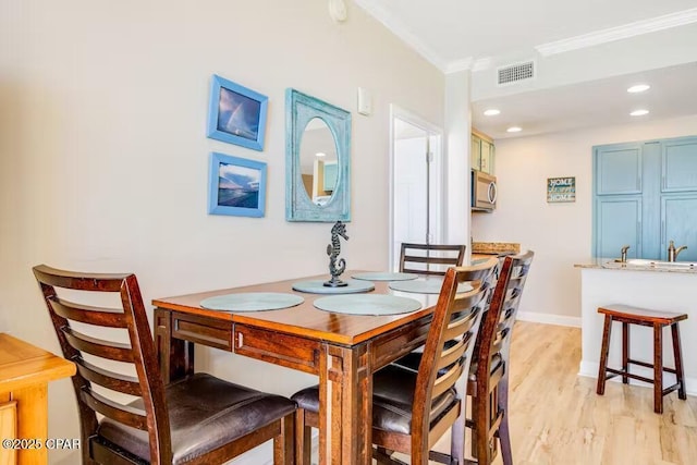 dining space with light wood-type flooring and crown molding