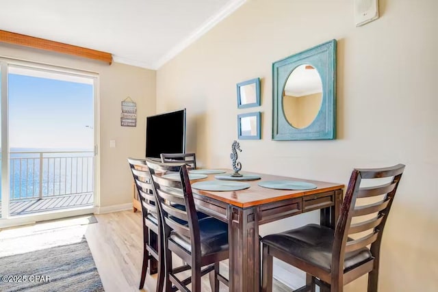 dining space with ornamental molding and light hardwood / wood-style flooring